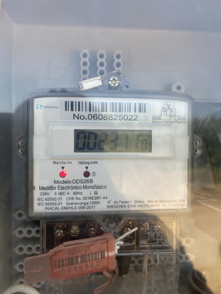 El medidor de consumo o suministro de energía es el dispositivo que se instala en la fachada exterior de la vivienda. Su función principal es registrar todo el consumo eléctrico que se genera dentro del hogar, de modo que cada mes se pueda emitir la factura correspondiente. En la zona marcada como “marcha inversa” aparece un LED que se ilumina cada vez que se detecta corriente eléctrica invertida.